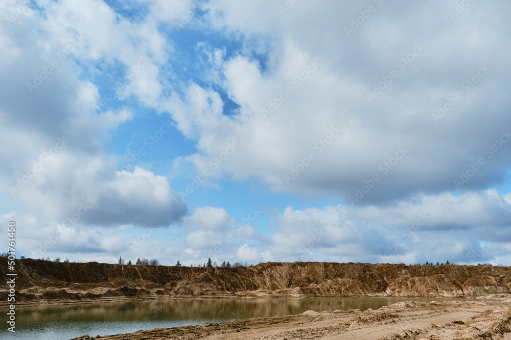 Artificially dug pits and ponds or lakes. Beautiful view of sand dunes and quarries with water in cloudy sunny weather in spring. Landscapes of Russia Moscow region.