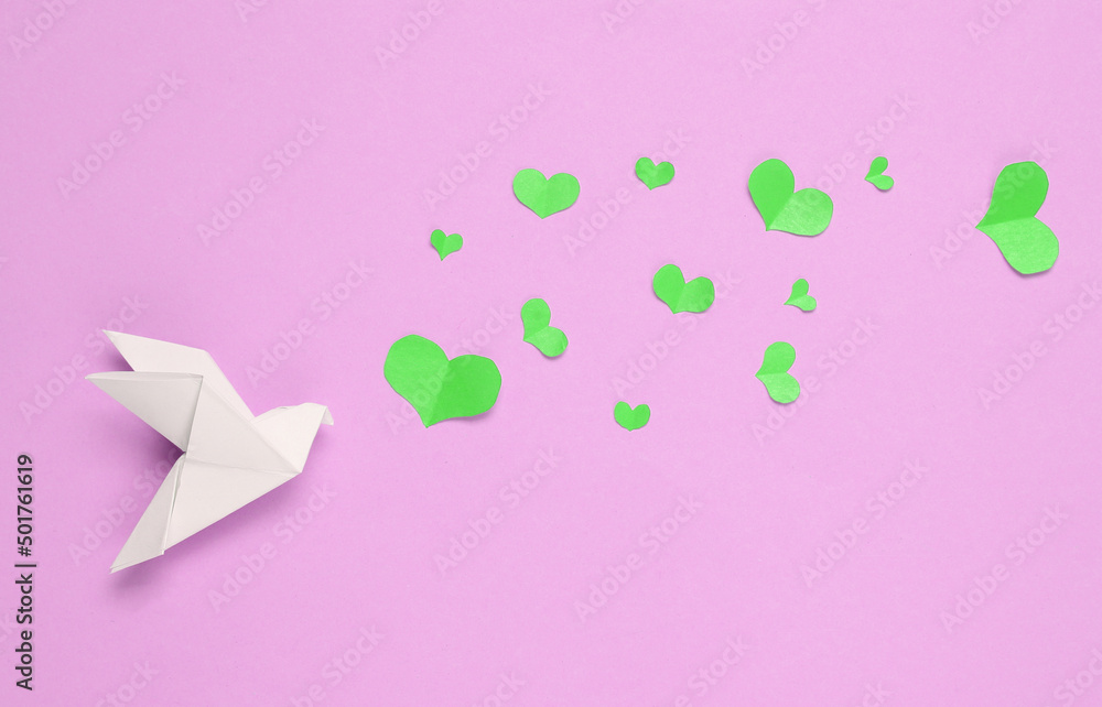 Origami dove with hearts on pink background. Peace and love. Top view Origami dove with hearts on pink background. Peace and love. Top view