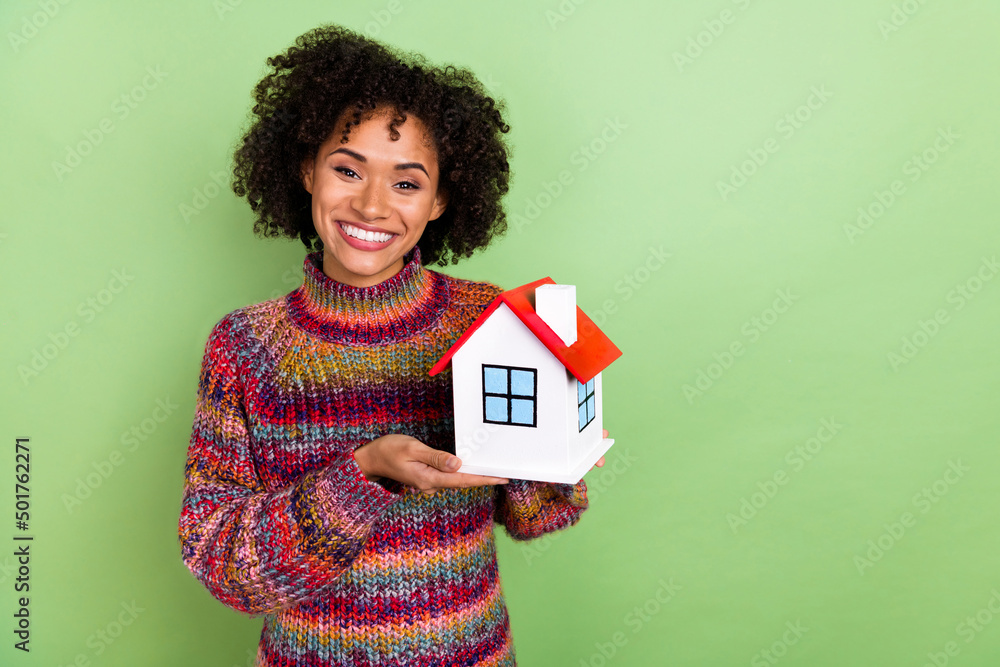 Photo of funny young curly hairstyle lady hold house wear red turtleneck isolated on green color background Photo of funny young curly hairstyle lady hold house wear red turtleneck isolated on green color background
