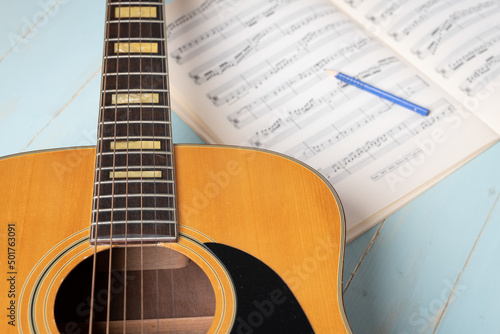 Music recording scene with guitar, music sheet and pencil on wooden table, closeup