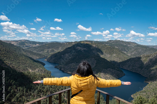 Mulher turista com os braços abertos como manifestação de alegria e liberdade no miradouro Olhos do tua em Castanheiro do Norte no concelho de Carrazeda de Ansiães com o rio Tua ao fundo photo