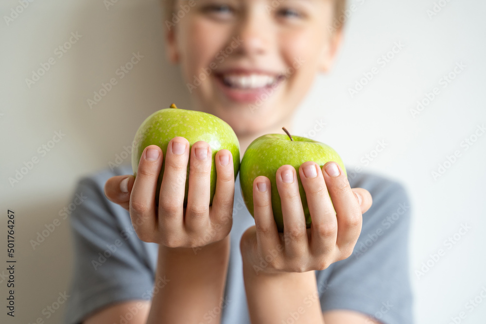 Smiling сhild held forward green apples in his hands over white background. Delicious and healthy food, proper nutrition. Smiling сhild held forward green apples in his hands over white background. Delicious and healthy food, proper nutrition.