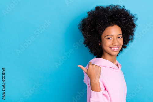 Profile side view portrait of attractive cheerful bushy haired girl showing copy space ad isolated over bright blue color background