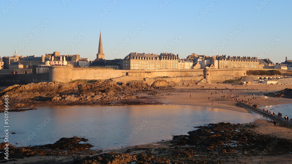 Panorama sur les remparts de la vieille ville de Saint-Malo, au bord de la mer, en Bretagne, avec la plage de Bon-Secours et le clocher de la cathédrale Saint-Vincent, au soleil couchant (France)
