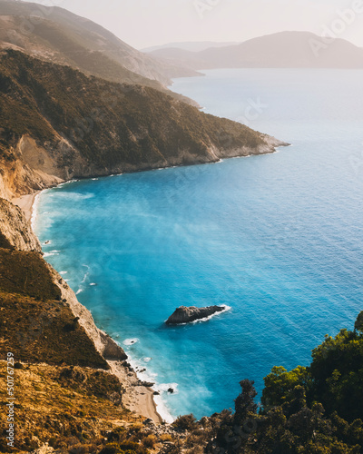 Kefalonian coast cliffs against hazy sky azure water of the Ionian Sea photo