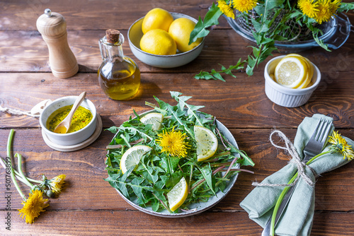 Dandelion salad with dip made with olive oil, lemon juice and spices on brown wooden table.