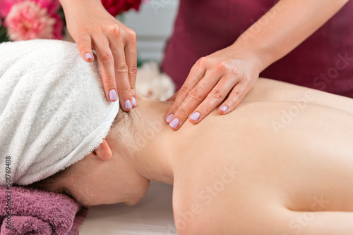 Masseur makes neck massage. Woman enjoying relaxing back massage in cosmetology spa centre