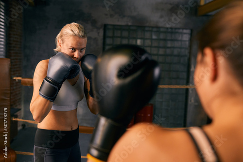 Horizontal over-the-shoulder shot of two young women starting boxing sparring match