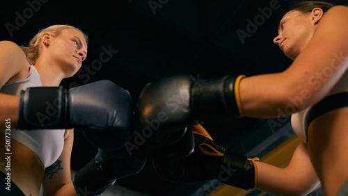 From below horizontal shot of two Caucasian women starting sparring match greeting each other