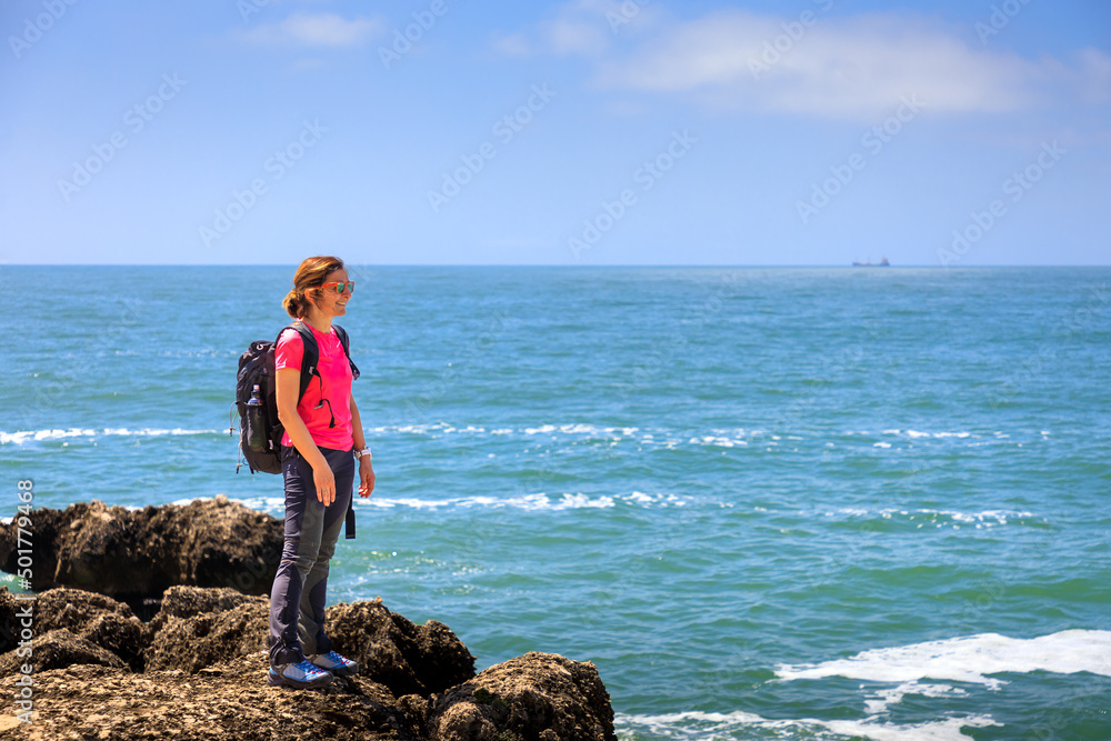 Hiking on the sea coast. Woman hiker explores the rocky sea coast. Concept of healthy life and outdoor activities in contact with nature.
