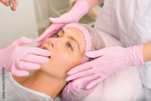 Image of a young beautiful woman dressed as a patient, lying on a couch in a cosmetology clinic.