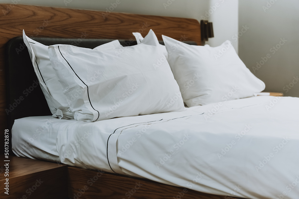 White pillows and sheets in a bedroom in a beauty salon. Close. Large double bed for comfortable sleep and relaxation. Modern comfortable white cotton bed linen. White pillows and sheets in a bedroom in a beauty salon. Close. Large double bed for comfortable sleep and relaxation. Modern comfortable white cotton bed linen.