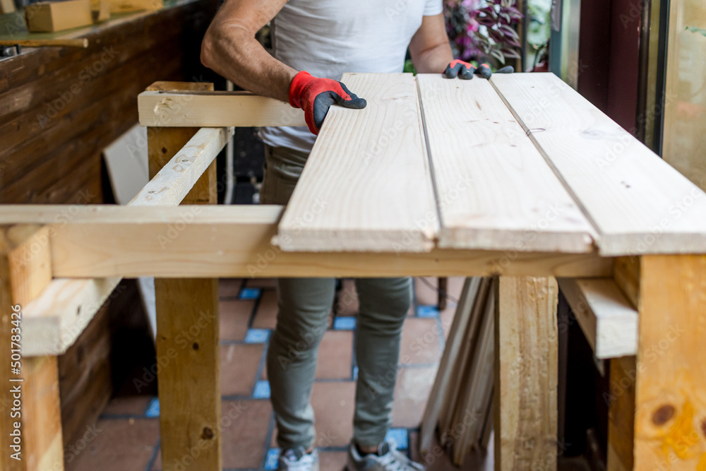 Man building a handmade wooden table with pine boards Man building a handmade wooden table with pine boards