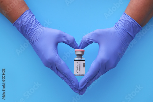hand in medical blue gloves in the shape of a heart hold medicines for covid 19