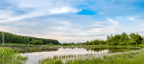 Summer landscape. Lake, forest and blue sky with beautiful clouds.