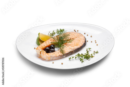 Red fish steak served on a white plate with olives, lemon and herbs, close-up, isolate. Steamed salmon steak with spices. Healthy seafood food