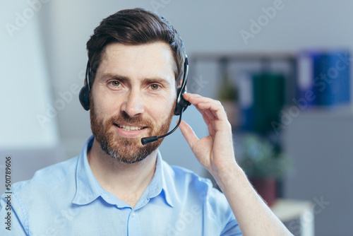 Close-up portrait of a businessman with a headset for a video call, a man looking at the camera smiling, a call center operator