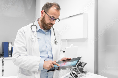 Doctor examine an x-ray image of a patient in digital tablet at doctor office. High quality photography.