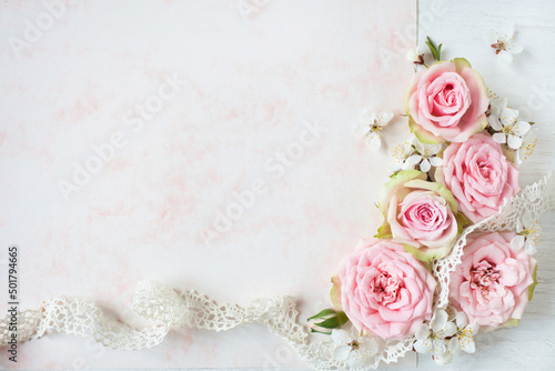 White-pink background with flowers of pink roses, blooming cherry plum, lace ribbon and space on paper for text congratulation, invitation. Greeting card for wedding, mother's day, birthday