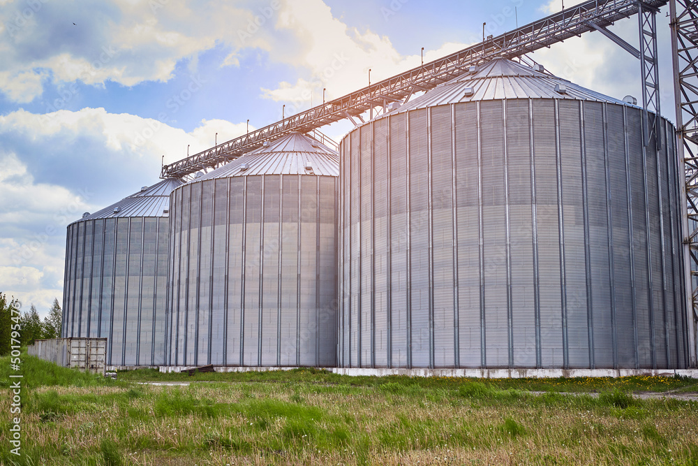 Metal elevator (grain silo) in agriculture zone. Grain Warehouse or depository is an important part of harvesting. Сorn, wheat and other crops are stored in it Metal elevator (grain silo) in agriculture zone. Grain Warehouse or depository is an important part of harvesting. Сorn, wheat and other crops are stored in it