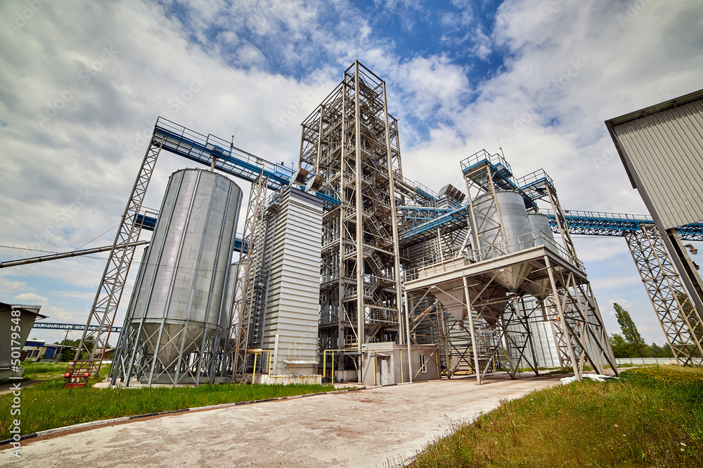 Metal elevator (grain silo) in agriculture zone. Grain Warehouse or depository is an important part of harvesting. Сorn, wheat and other crops are stored in it Metal elevator (grain silo) in agriculture zone. Grain Warehouse or depository is an important part of harvesting. Сorn, wheat and other crops are stored in it