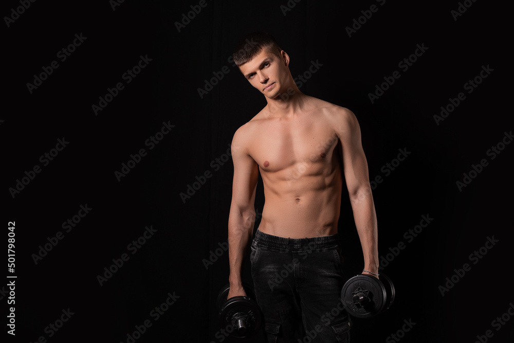 strong muscular sexy man with dumbbells on a black background