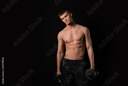 strong muscular sexy man with dumbbells on a black background