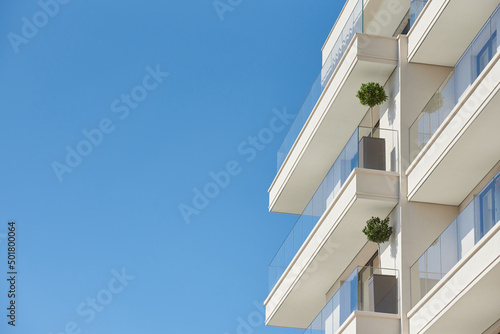 Balcony with glass railing in a modern apartment building against a blue sky wit Fototapet