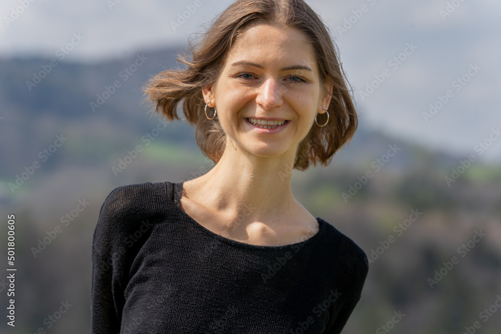 Portrait of young beautiful natural woman smiling at camera in nature of Switzerland in springtime at sunshine.