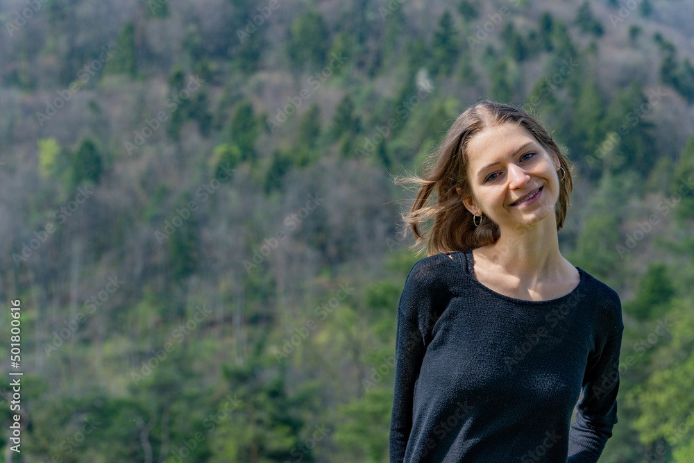 Portrait of young beautiful woman smiling at camera in nature of Switzerland in springtime. Copy space.