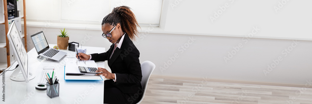 Smiling Businesswoman Calculating Invoice On Computer Smiling Businesswoman Calculating Invoice On Computer