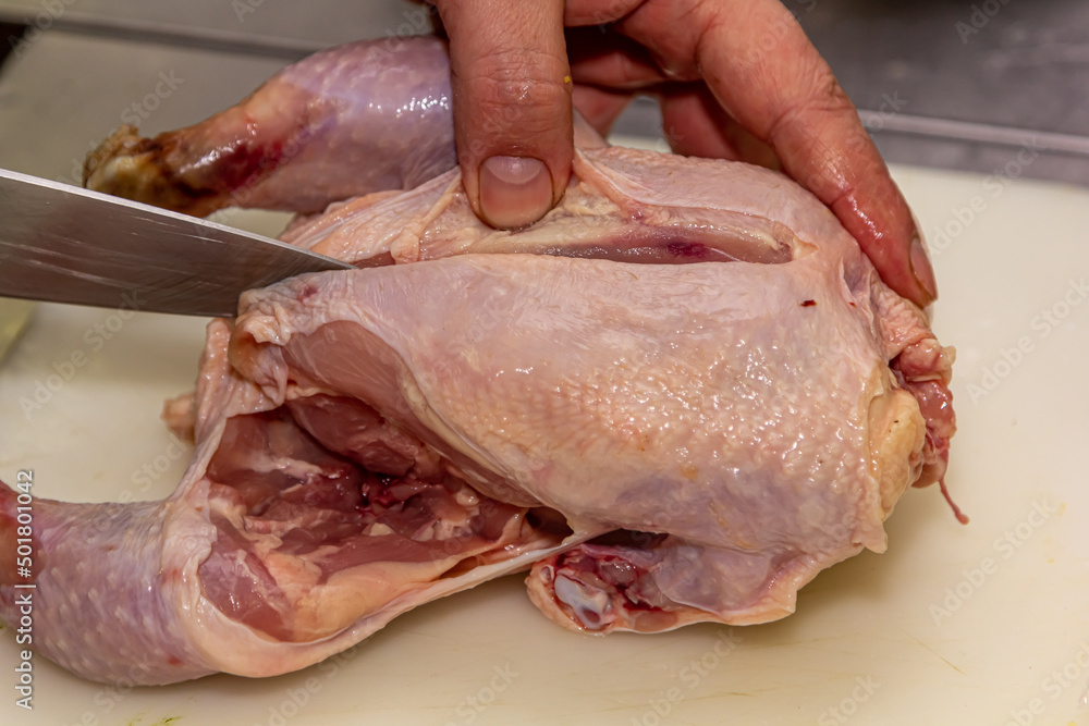Chef carves a whole chicken carcass on a wooden Board, the view from above Chef carves a whole chicken carcass on a wooden Board, the view from above