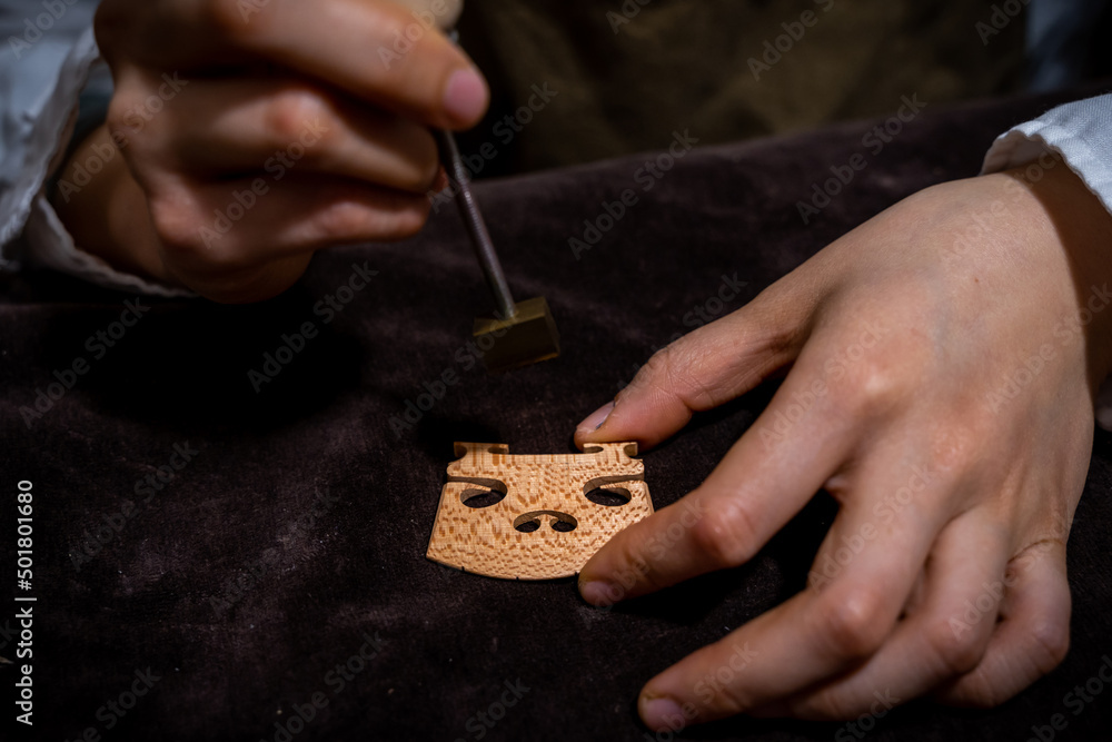 Fototapeta premium young Chinese woman violin maker signs the jumper of her violin with fire with her name