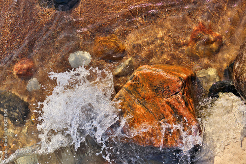 Directly Above Shot of Small Waves Rolling into Beach Dotted with Colorful Rocks and Boulders