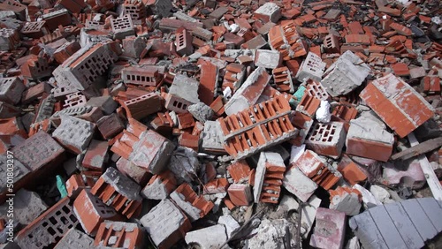 Closeup top view 4k video footage of ruines of ukrainian city after attack of russian occupiers during war in 2022 in Ukraine. Many pieces of broken red bricks laying on ground. Abstract background photo
