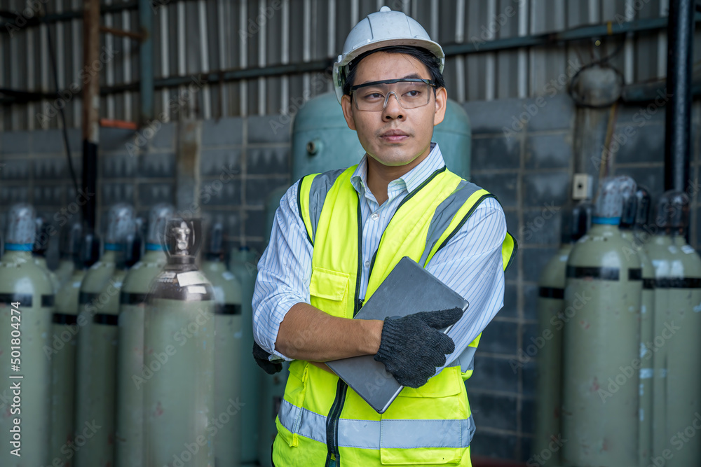 Foreman or Professional technician holding tablet in an industrial factory. Industrial worker holding tablet in manufacturing gas. Acetylene and oxygen gas steel storage tanks for factory. Foreman or Professional technician holding tablet in an industrial factory. Industrial worker holding tablet in manufacturing gas. Acetylene and oxygen gas steel storage tanks for factory.