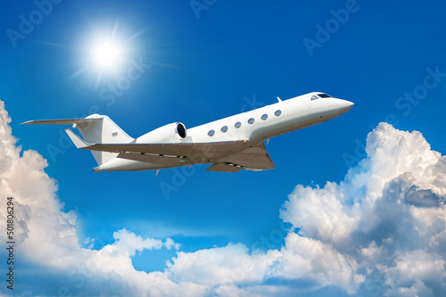 White modern luxury private jet flies in the air above the clouds