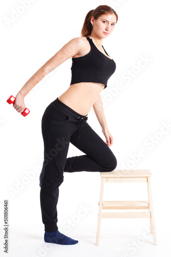 Female fitness model excercising in studio with dunbell weights and doing a floor routine of stretches and lifts on a matt. photo