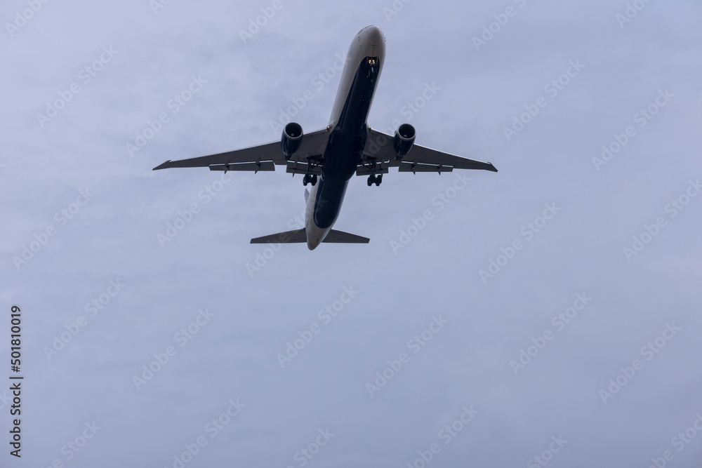 Fototapeta premium Jet plane seconds before landing on blue sky on a sunny day of aircraft silhouette seen from ground at international airport