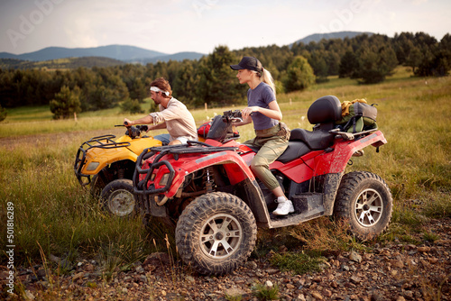 Two tourist friends driving quads together; Active vacation concept