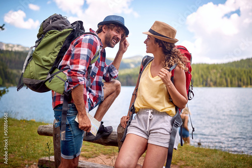 A young couple is having romantic moments while making a break at the lake during hiking the mountain. Trip, nature, hiking