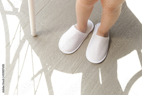 Child in blank white hotel slippers. Towelling disposable spa guest shoes. Top view.	