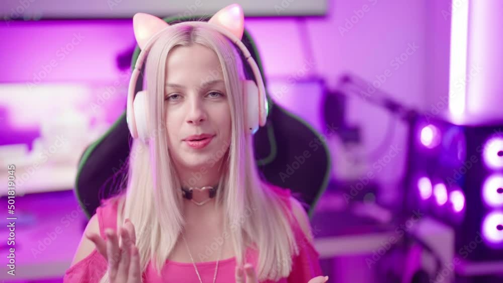 Cute blonde gamer girl with cat ear headphones in cyberspace interacting to fans 4K Cute blonde gamer girl with cat ear headphones in cyberspace interacting to fans 4K