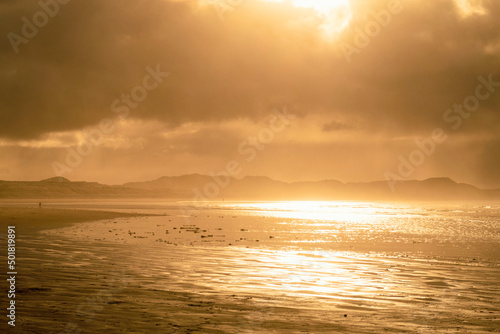 Beautiful sunset above sea or ocean. Vibrant and soft colors  magic light. Small clouds on the sky  reflection of sun in the water and sand on beach. Concept of romantic time on vacation in tropical.