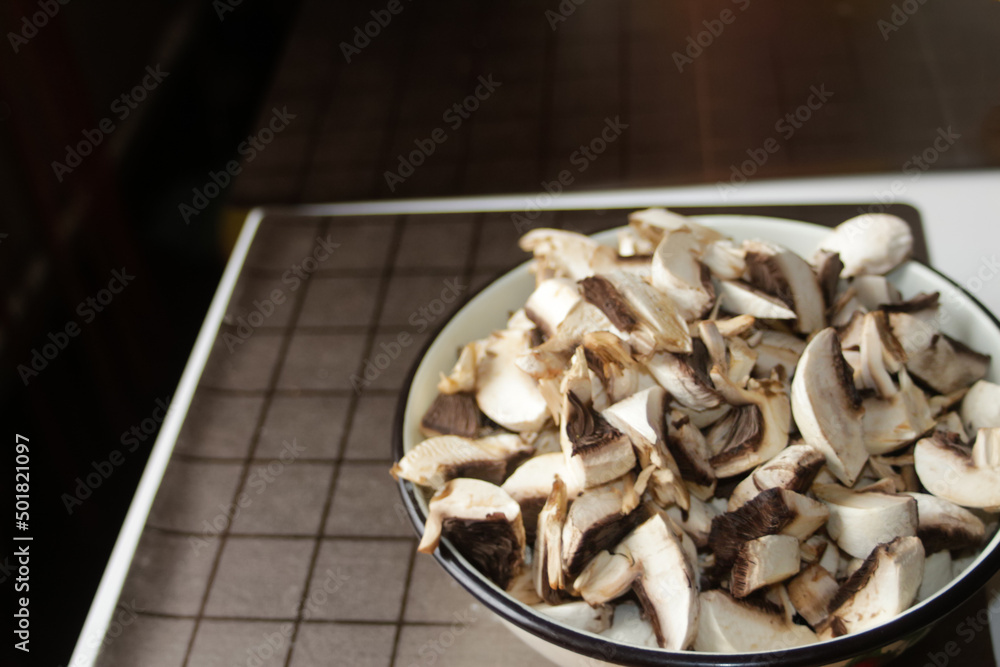 Defocus raw mushrooms in the bowl on dark background on the kitchen. Many cut champignon for pizza. Vegan concept. Out of focus Defocus raw mushrooms in the bowl on dark background on the kitchen. Many cut champignon for pizza. Vegan concept. Out of focus