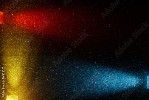 On a dark blue background in a small multi-colored grain  rays of red yellow and light blue light