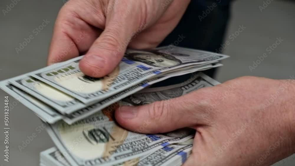 a businessman is counting cash. close-up of male hands counting a stack of hundred-dollar US banknotes. the concept of investment, money exchange, bribes or corruption. selective focus. a businessman is counting cash. close-up of male hands counting a stack of hundred-dollar US banknotes. the concept of investment, money exchange, bribes or corruption. selective focus.