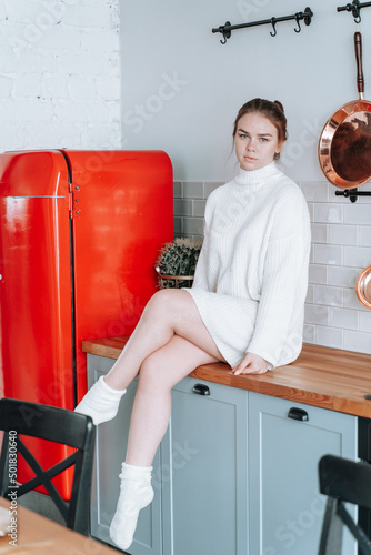 the girl is sitting on the kitchen table