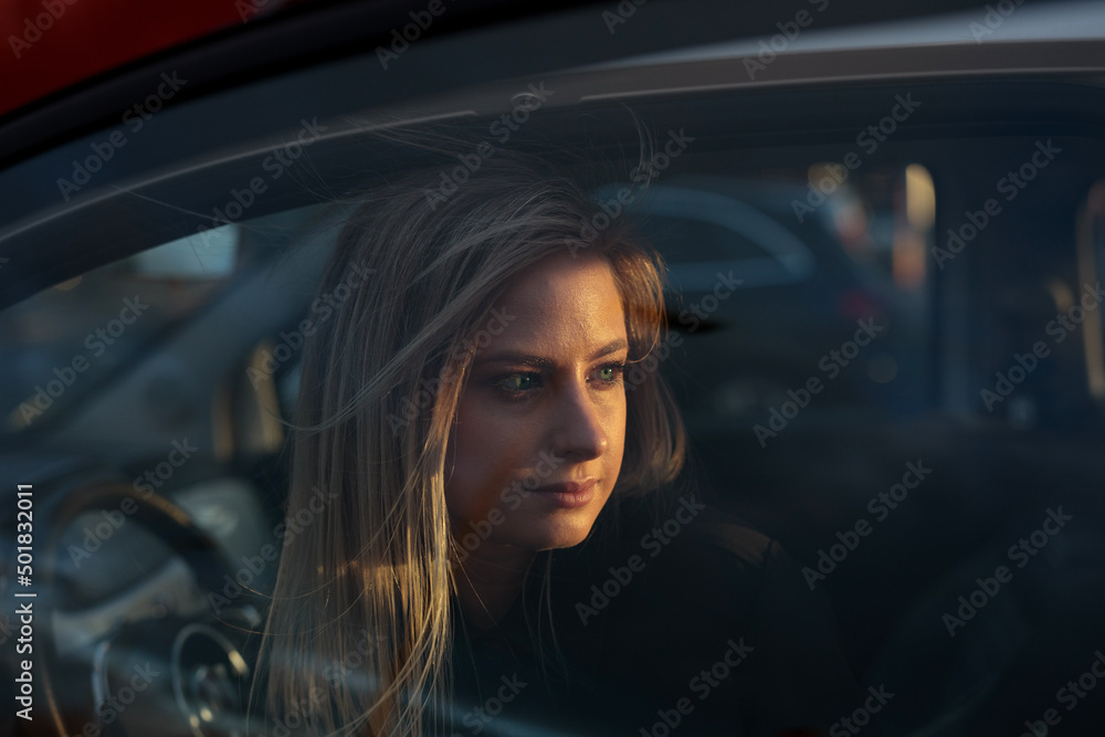 Frau bei Sonnenuntergang in der Stadt mit Auto bei Wind Frau bei Sonnenuntergang in der Stadt mit Auto bei Wind