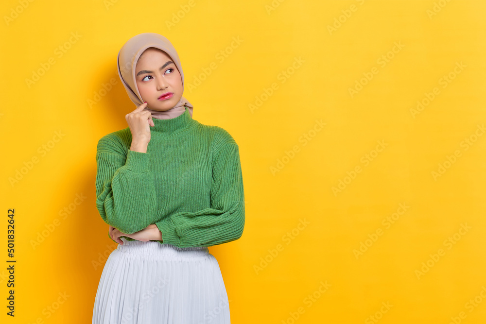 Pensive beautiful Asian woman in green sweater thinking about something and looking away isolated over white background Pensive beautiful Asian woman in green sweater thinking about something and looking away isolated over white background